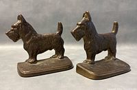 Pair of cast metal Scottish Terrier bookends in profile, showing detailed fur texture, standing on flat rectangular bases with minor wear.