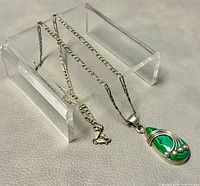 Silver chain and malachite pendant displayed on clear stand, showing chain length and pendant details