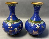 Pair of Chinese cloisonné enamel bud vases showing front view with floral motifs on blue background and gold rims