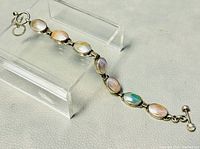 View of the bracelet displayed on a clear acrylic stand showing the stones and silver links.