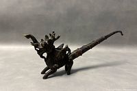 Side view showing the full length and shape of the bronze Qilin pipe, with details of the head, body, legs, and pipe extending back.