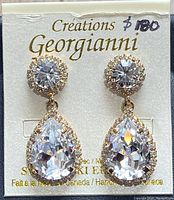 Pair of gold-toned Swarovski crystal teardrop earrings on branded backing card.