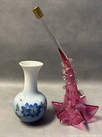 Front view of porcelain and cranberry glass vases side by side on neutral background