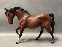 Side view of the brown Beswick porcelain horse figurine with black mane, tail, and white leg markings.