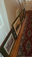 Four large framed wall art pieces lined up on floor against wall, showing their sizes and condition of frames