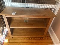 Front angle view of the 2 shelf faux pine wood bookcase showing the two shelves, wood grain, paint marks and surface wear.
