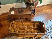 Wooden box and woven basket placed on hardwood floor next to decorative ceramic pot.