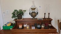 Full view of items on wooden desk with vintage electric oil lamp, faux plant, multiple candles, and candle holders