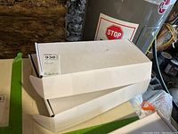 Two boxed faucet units placed on a surface near a water heater, showing model labels and brand names.