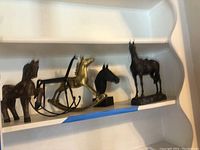 Multiple horse figurines including wood, brass rocking horse, cast iron horse