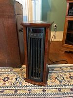 Front view of electric room heater showing wood casing and black grille with control panel.