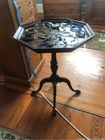 Full view of vintage wooden side table with hexagonal top and various items on top.