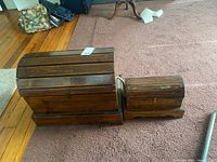 Photo of two pine wood trunks with domed lids placed on carpeted floor showing size comparison.