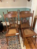 Front and side view of four vintage carved wooden chairs with cane seats, showing the overall set and condition