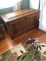 Front side of the vintage wooden chest showing panel design, lock keyhole, and condition of wood surface.