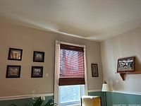 Room wall showing arrangement of four African wildlife prints next to window and fabric horse plaque mounted on a small wooden shelf.