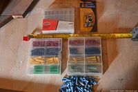 Overview showing two boxes of wall plugs, pile of blue wall plugs, unopened drill bit container, sealed depth stops.