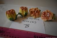 Two pairs of ceramic flower-shaped salt and pepper shakers placed on paper with a note 'Salt & Pepper Shakers B' and a ruler for scale.