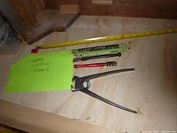 Overview of three glass cutting tools including snips and cutters on wooden surface with measuring tape and green note