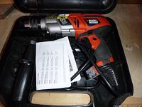 Full view of the Black and Decker hammer drill in case, showing drill, side handle, manual, and cord.
