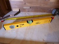 Yellow Johnson Hot Shot level lying flat on a wooden surface with a tape measure alongside it.