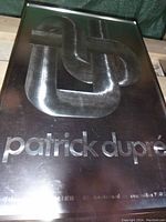 Front view of framed foil print showing abstract metallic knot and ‘patrick dupré’ text.