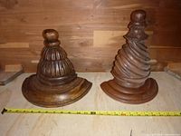 Front view of both sconce shelves showing different carved decorative tops and bases with tape measure for size reference.