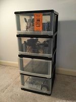 Full view of the four drawer plastic storage unit closed showing semi-transparent drawers and black frame.
