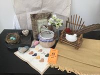 Overview of farmhouse decor items including heart quilted hanging, ceramic basket, woven runner, twig chair, and glass hen trinket box.
