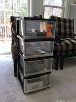 Full view of 4 drawer plastic storage tower containing crafting supplies, placed next to chairs