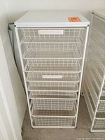 Front view of the white metal storage rack with eight wire mesh drawers.