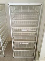 Front view of white Elfa storage rack with 8 wire basket drawers in used condition.