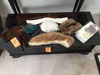 Assortment of vintage faux fur accessories and craft materials spread out on a black cabinet