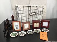 Full lot with porcelain plates, wooden frames, wooden stands, and wire basket on white background