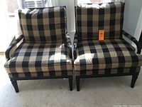 Front view of two large armchairs placed side by side on carpeted floor near window.