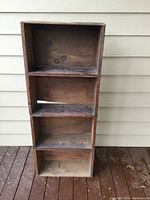 Full front view of the vertical shelf showing four compartments made from stacked prune crates