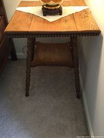 Front view of square oak table showing the wood grain top with ball trim and ornate turned legs.