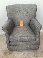 Front view of gray tweedy swivel chair showing cushioned seat, flared armrests, and high slightly curved backrest.