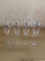 Front view of all 8 champagne flutes displayed in two rows on a wooden surface.