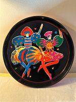 Front view of the Cirque Du Soleil tin serving tray showing colorful figures and text design on black background