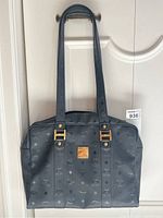 Front view of black MCM shoulder bag hanging on door