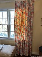 Curtains hanging in front of window showing full length and pleated style.