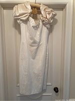 Front view of the cream cotton pique dress with satin puff sleeves and pearl details on bodice.