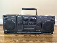Front view of Sony CFD-440 stereo with both speakers attached, showing control panel and CD player lid closed.