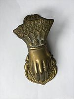 Front view of the solid brass hand-shaped receipt holder showing detailed cuff and ring on finger