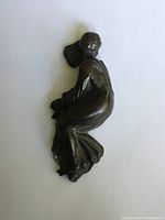 Top view of small antique bronze lady figure paperweight showing seated woman in flowing dress with visible folds and details