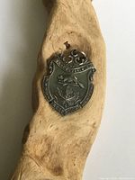 Front of antique sterling silver fob pendant showing detailed embossed shield with winged figure, maple leaf, and inscriptions 'Vancouver BC' and 'Root Tech Pilot'.