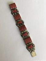 Full view of the large chunky silver bracelet laid flat showing six linked panels with coral insets and a clasp at one end.