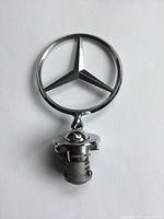 Front view of Mercedes Benz hood ornament showing three-pointed star emblem and mounting base.