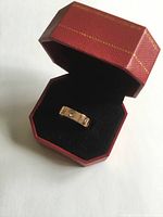 Open red Cartier octagonal box showing rose gold ring centered on black velvet interior